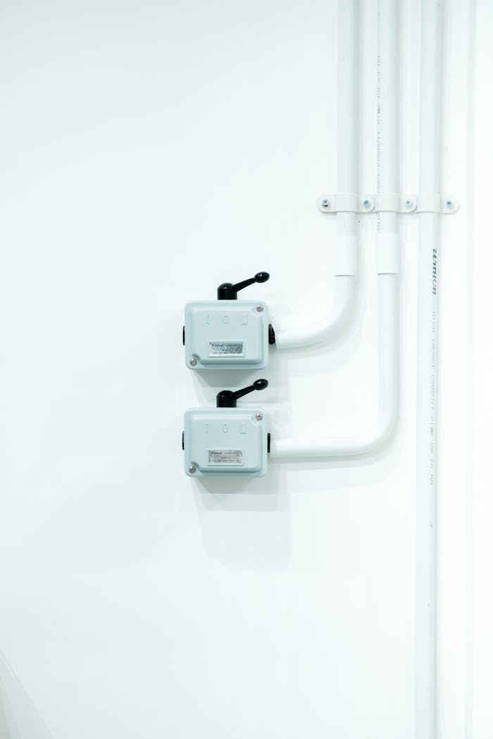 Clean and modern electrical switches mounted on a white wall with piping.