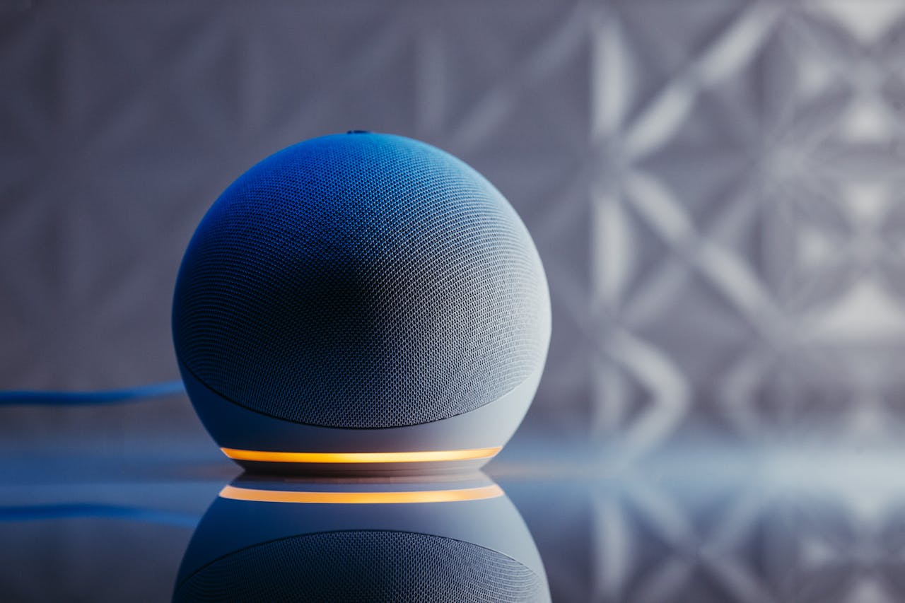 Close-up of a modern smart speaker in a stylish setting with illuminated base and reflection.